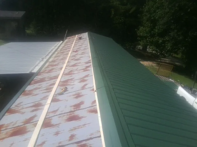 Old rusted panels beside newly installed green metal roofing — Wind Damage Roof Repair by Roofing Brothers in Lapel