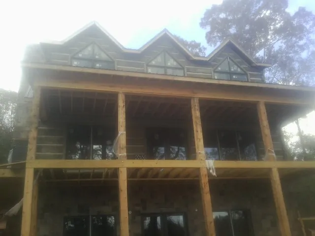 Dormers and porch framing on a large log home under construction — Roof Coating work by our crew in Lapel