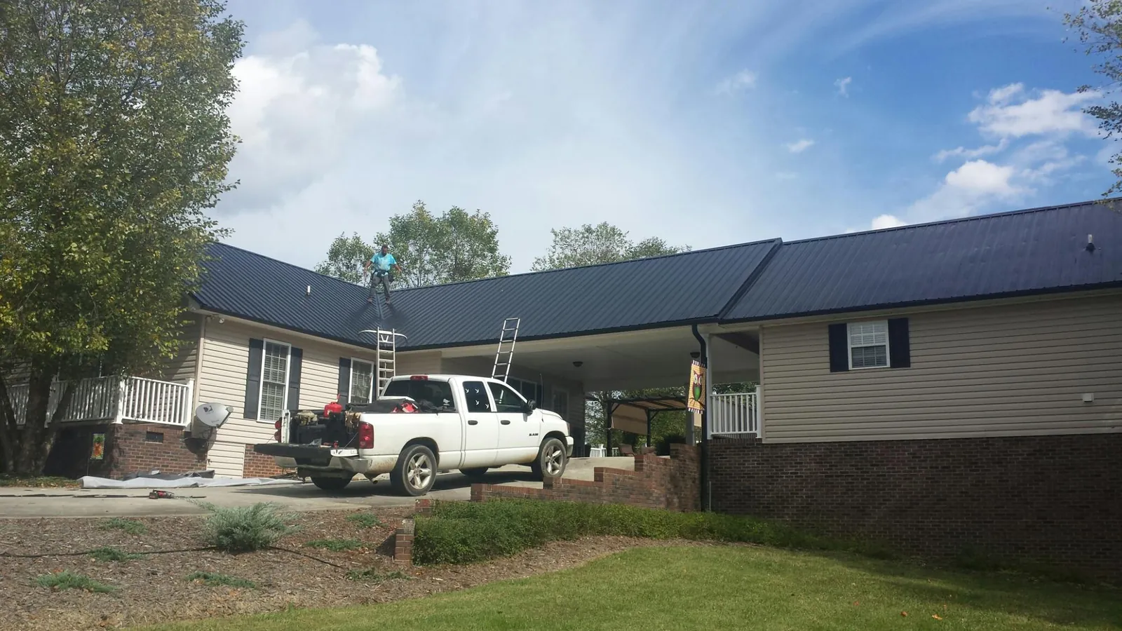 Black metal roof over a home and attached breezeway with ladders set in Lapel