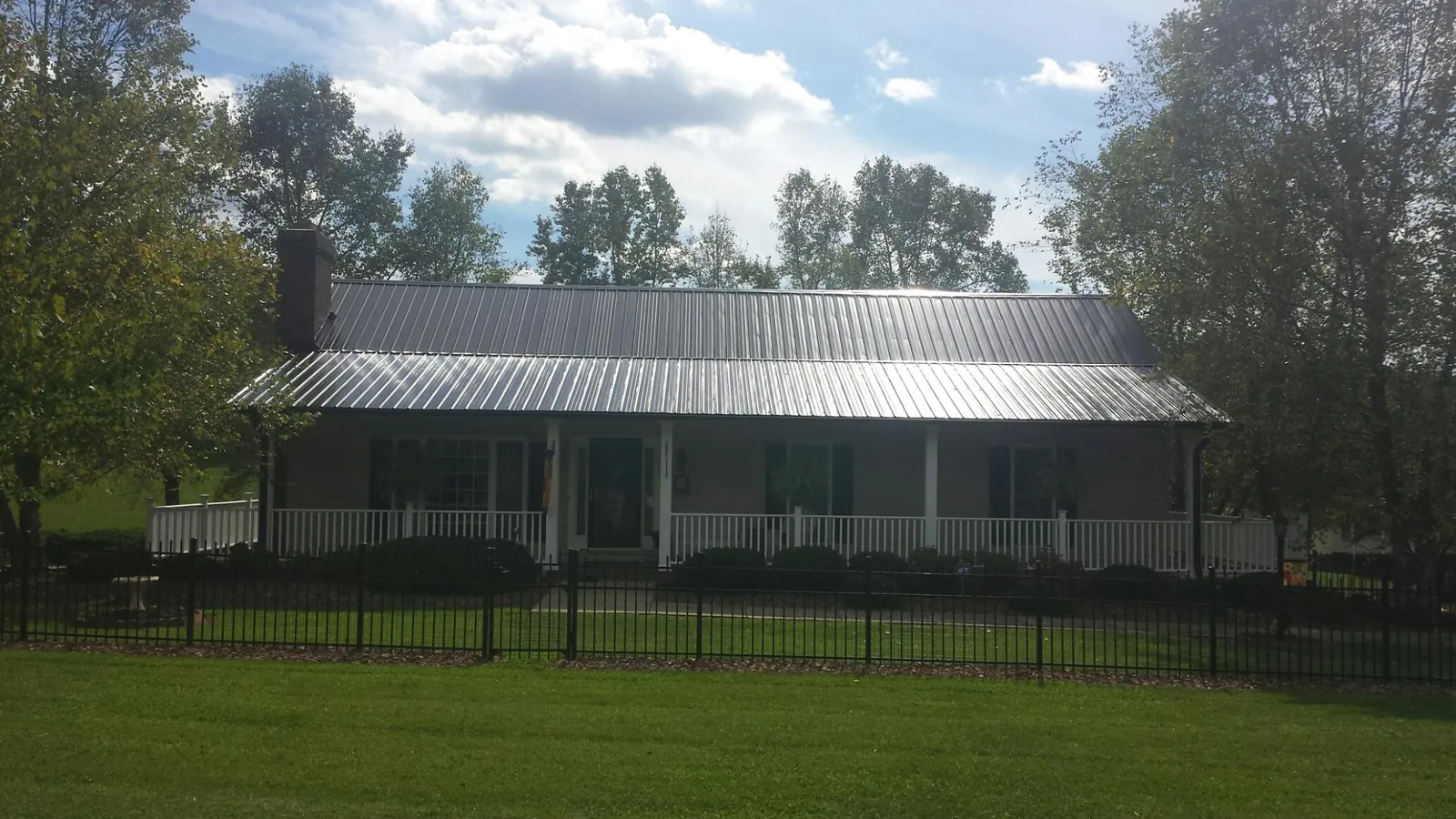 Gray metal roof on a brick ranch with a full width front porch — Gutter Guard Installation work by our crew in Lapel