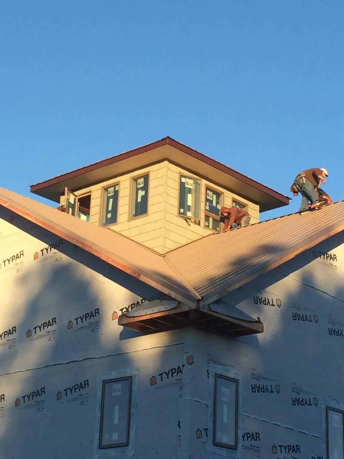 Roofers working around a rooftop cupola on a new metal roof at sunset — Roof Waterproofing in Lapel by Roofing Brothers